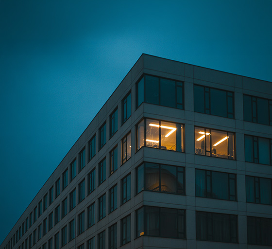 Exterior view of an office building at night, where one office has the lights on