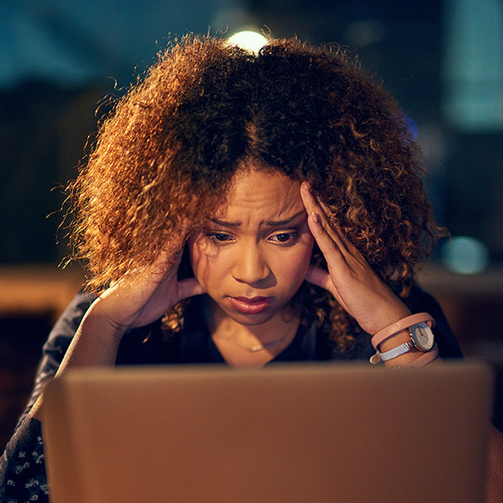 An african-american woman sitting in front of a laptop with a confused expression on her face